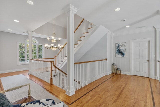 staircase featuring ornate columns, hardwood / wood-style floors, and a notable chandelier