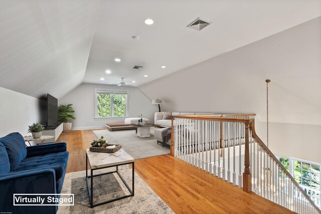 living room featuring ceiling fan, vaulted ceiling, and light hardwood / wood-style flooring