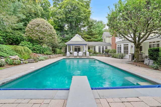 view of pool with a patio area, a diving board, french doors, and an outdoor structure