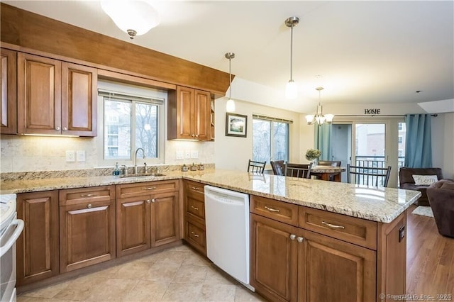 kitchen with pendant lighting, dishwasher, kitchen peninsula, and sink