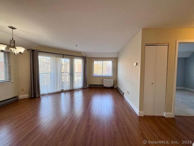 empty room with lofted ceiling, baseboard heating, dark hardwood / wood-style flooring, and an inviting chandelier