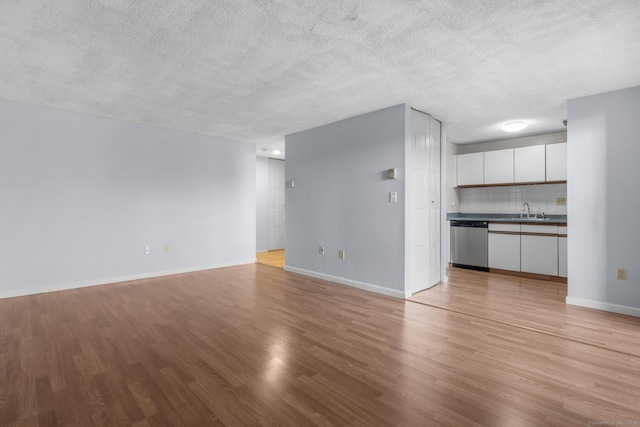 unfurnished living room with a textured ceiling, light hardwood / wood-style flooring, and sink