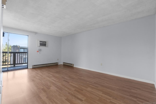 spare room featuring a wall mounted AC, a baseboard heating unit, a textured ceiling, and hardwood / wood-style floors