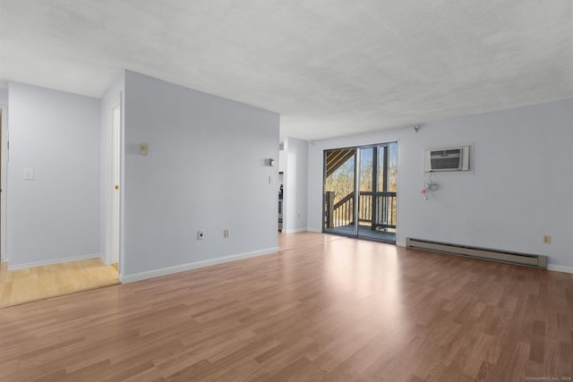 empty room featuring light hardwood / wood-style floors, a baseboard radiator, a textured ceiling, and a wall mounted AC