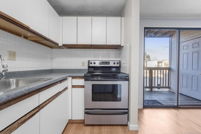 kitchen featuring light hardwood / wood-style flooring, decorative backsplash, white cabinetry, and stainless steel range with electric stovetop