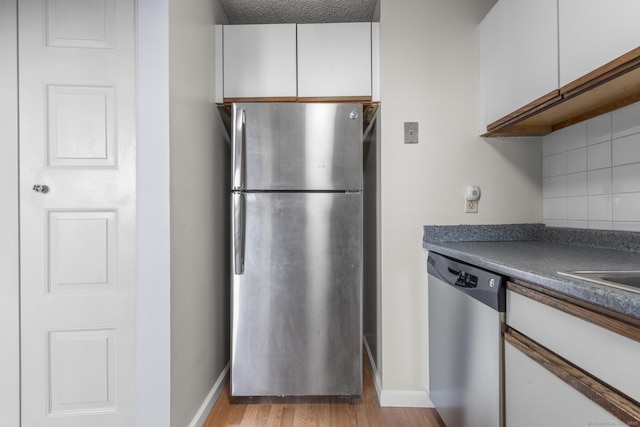 kitchen featuring appliances with stainless steel finishes, tasteful backsplash, light wood-type flooring, a textured ceiling, and white cabinets