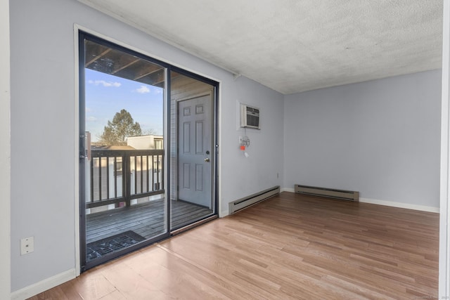 interior space featuring light wood-type flooring, baseboard heating, a textured ceiling, and a wall mounted air conditioner