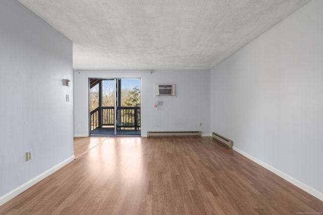 unfurnished room featuring a baseboard radiator, wood-type flooring, a textured ceiling, and a wall mounted AC