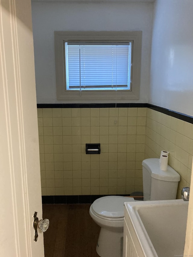 bathroom with sink, tile walls, and toilet