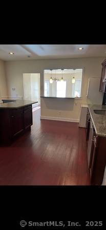 kitchen with dark wood-type flooring, dark brown cabinetry, light stone countertops, and sink