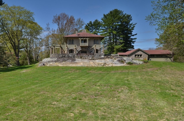 back of house with stone siding, a lawn, and stairway