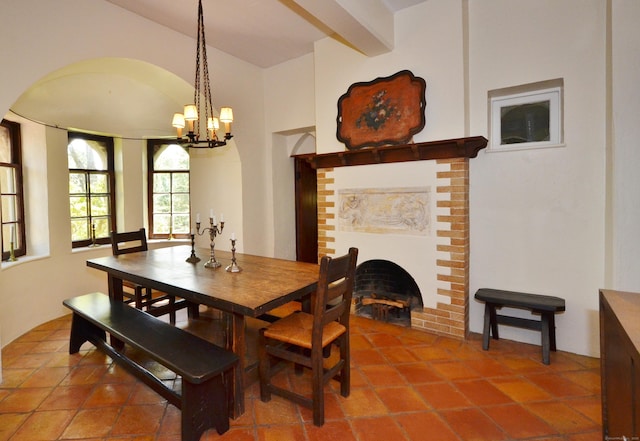 dining room with a brick fireplace, beam ceiling, and an inviting chandelier