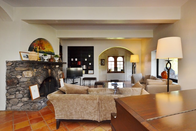 living room with arched walkways, beam ceiling, a stone fireplace, and tile patterned floors