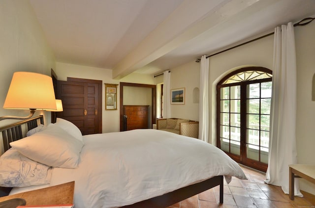 bedroom featuring french doors, beam ceiling, multiple windows, and stone tile flooring