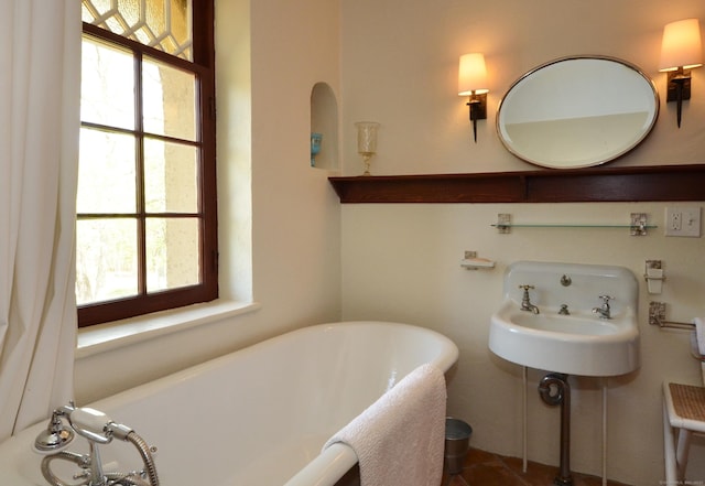 full bathroom with a freestanding tub and a sink