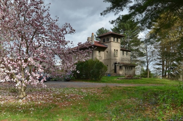 exterior space with a lawn, a chimney, and stucco siding