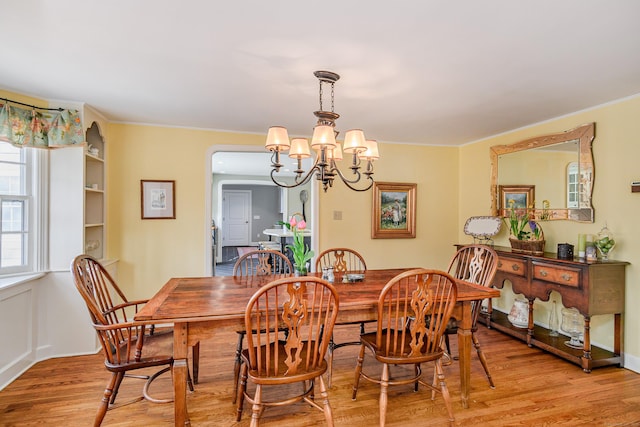 dining area with crown molding, a chandelier, and light wood-type flooring