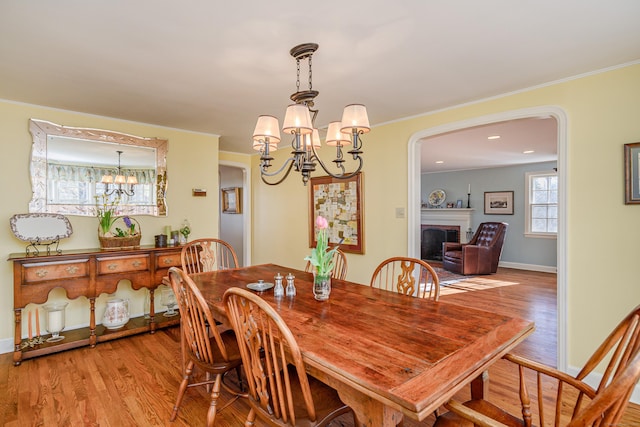 dining space with an inviting chandelier, ornamental molding, and light wood-type flooring