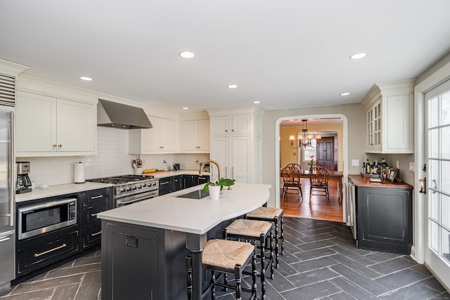 kitchen featuring white cabinetry, appliances with stainless steel finishes, sink, and wall chimney range hood