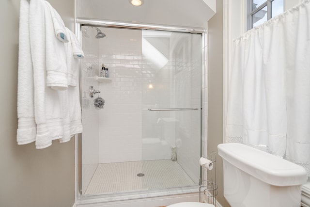 bathroom with toilet and a shower with shower door