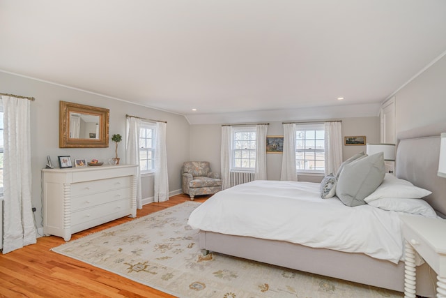 bedroom featuring vaulted ceiling, radiator, and light hardwood / wood-style flooring