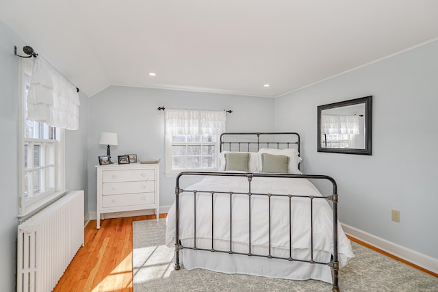 bedroom featuring lofted ceiling, radiator, and light wood-type flooring