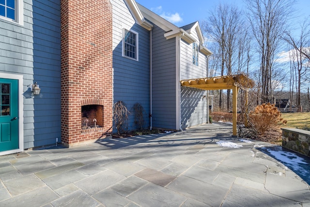 view of home's exterior featuring an outdoor brick fireplace, a patio area, and a pergola