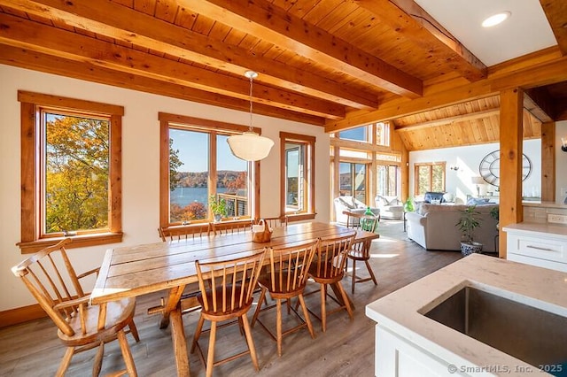 dining area with wood ceiling, plenty of natural light, and a water view