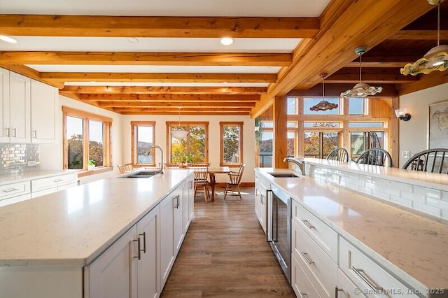 kitchen with sink, a large island, beam ceiling, and hanging light fixtures