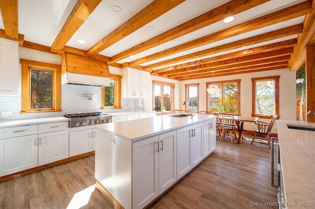 kitchen featuring beamed ceiling, stainless steel gas cooktop, hanging light fixtures, and white cabinets