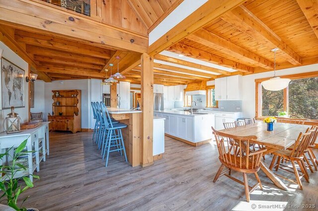 dining space with sink, wooden ceiling, beamed ceiling, and light wood-type flooring