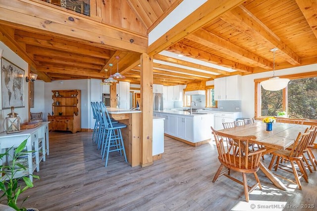 kitchen featuring hanging light fixtures, white cabinetry, light countertops, and beam ceiling