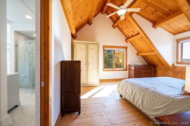 bedroom featuring multiple windows, vaulted ceiling with beams, ceiling fan, and ensuite bathroom