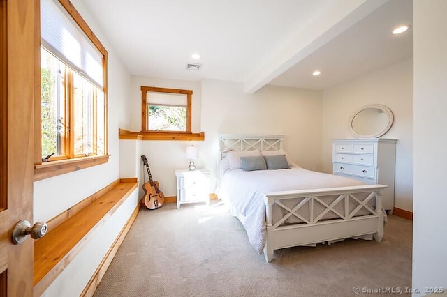 bedroom with beamed ceiling, multiple windows, and carpet