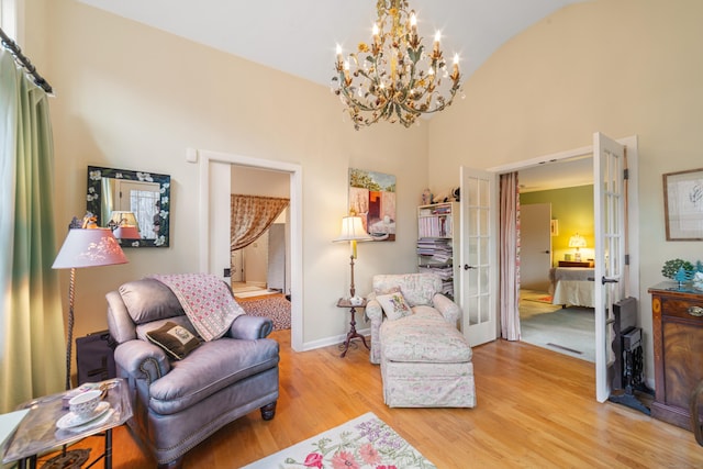 living area featuring vaulted ceiling, french doors, a chandelier, and light hardwood / wood-style floors