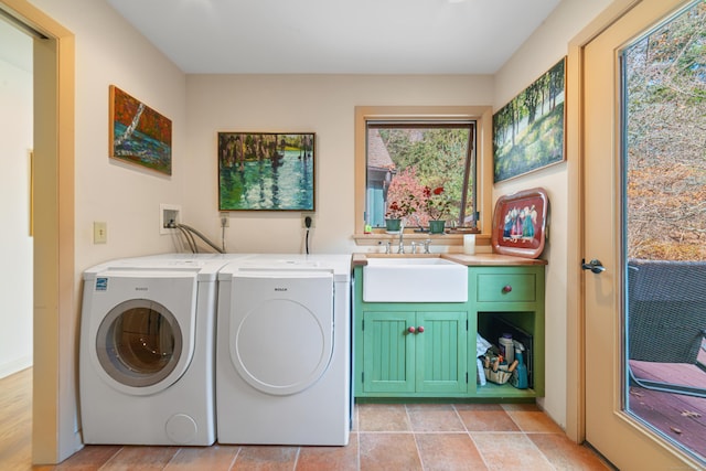 laundry area with washing machine and dryer, cabinets, and sink