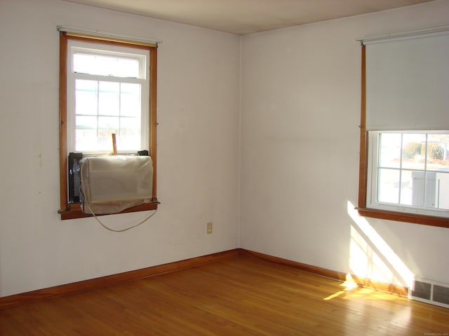 spare room with cooling unit, hardwood / wood-style floors, and a healthy amount of sunlight