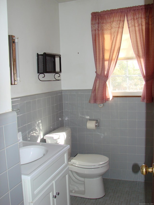 bathroom with tile patterned floors, vanity, toilet, and tile walls