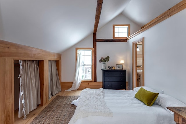 bedroom featuring multiple windows, light hardwood / wood-style flooring, and lofted ceiling