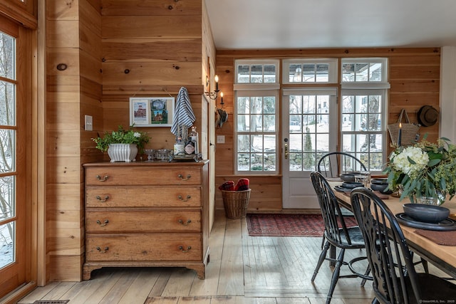 dining area with light hardwood / wood-style floors and wood walls