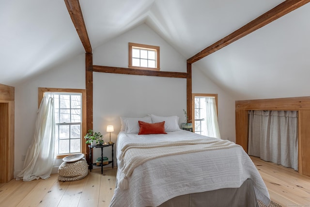 bedroom featuring multiple windows, light hardwood / wood-style flooring, and vaulted ceiling with beams