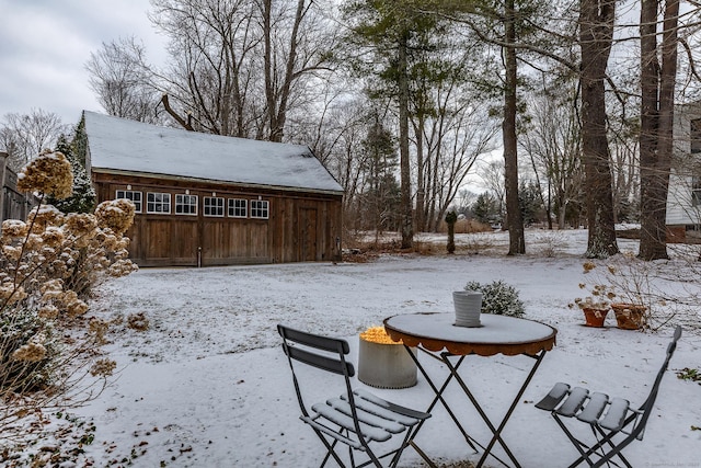 yard covered in snow with a garage and an outdoor structure