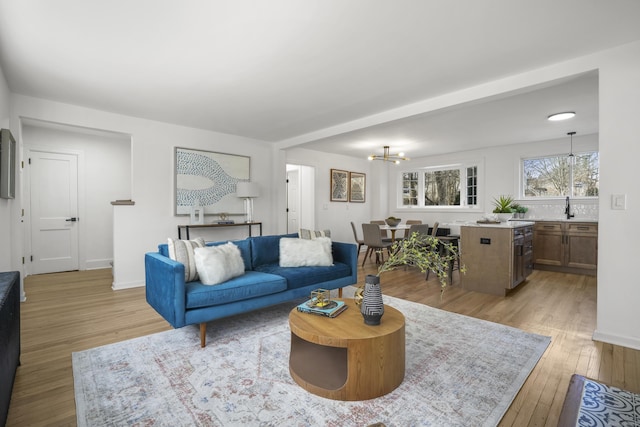 living room with sink, light hardwood / wood-style flooring, and a notable chandelier