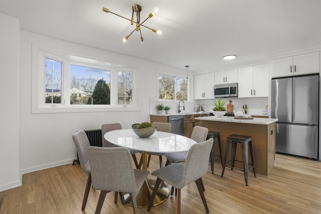 dining area featuring light hardwood / wood-style floors, sink, and an inviting chandelier