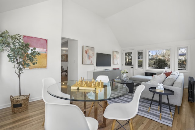 dining room featuring high vaulted ceiling and light hardwood / wood-style flooring