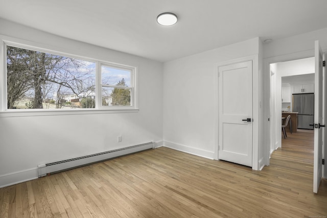 empty room featuring baseboard heating and light hardwood / wood-style flooring