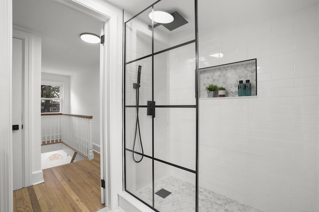 bathroom with a tile shower and wood-type flooring