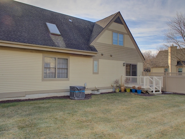 rear view of property featuring a wooden deck and a lawn