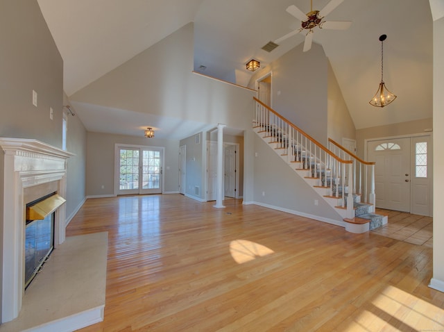 unfurnished living room featuring high vaulted ceiling, ceiling fan, a high end fireplace, and light hardwood / wood-style floors