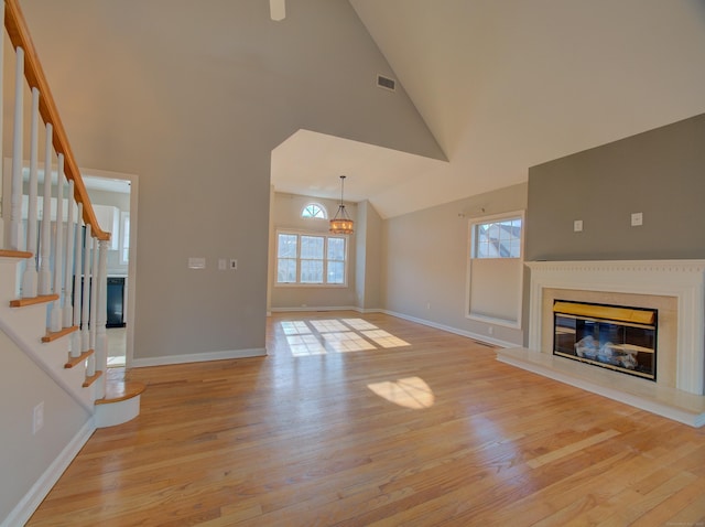 unfurnished living room featuring light wood-type flooring and high vaulted ceiling